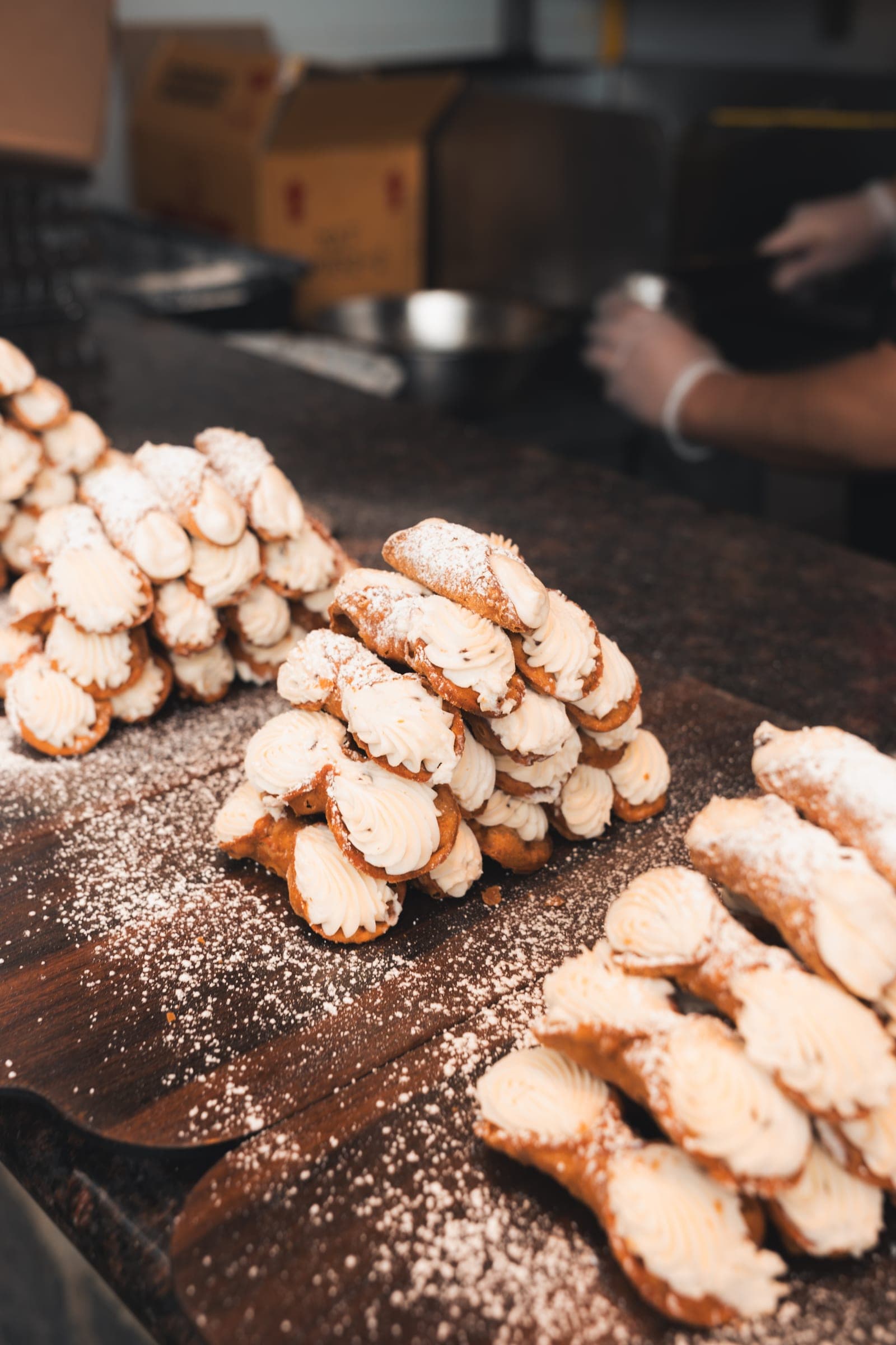 A tray of cannoli dusted with powdered sugar at a vendor stand